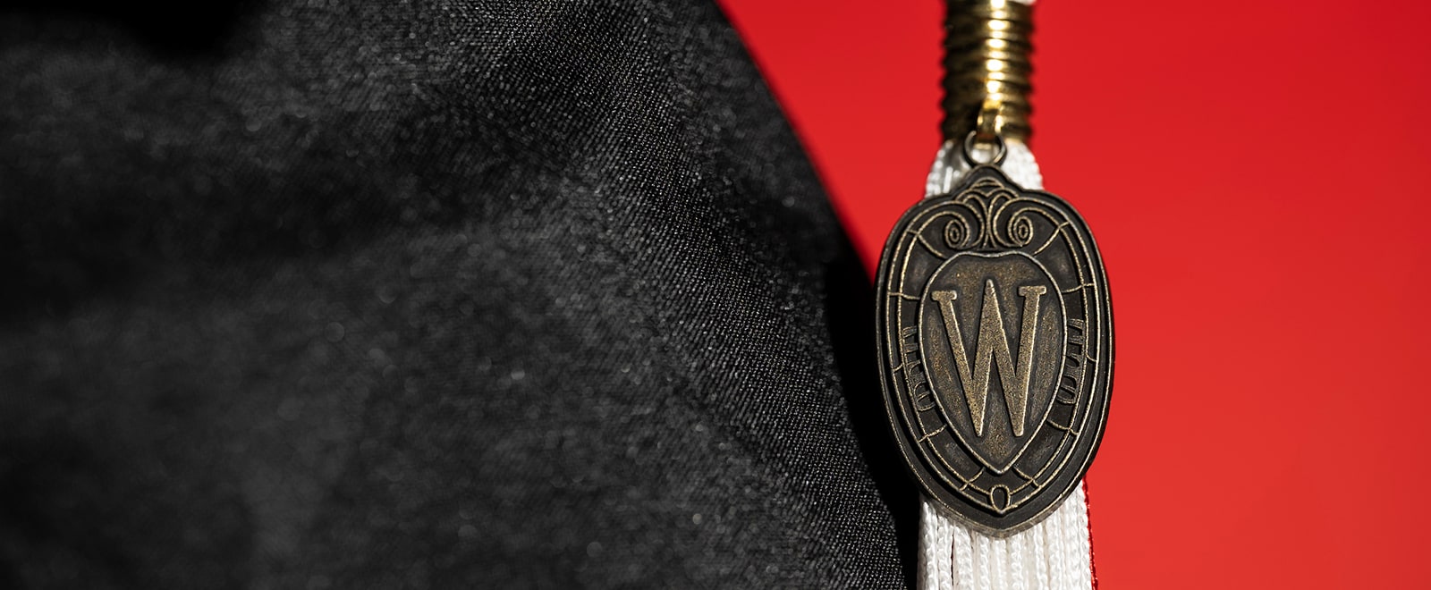 Close-up image of a UW Crest pendant on the tassel of a mortarboard.