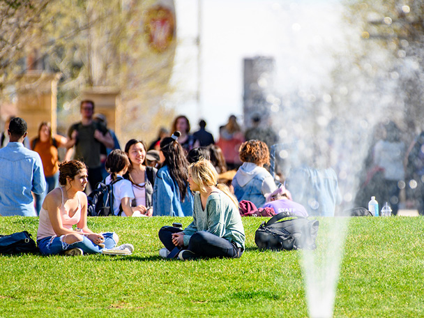 华盛顿大学的学生和行人在图书馆购物中心的喷泉旁享受温暖的春天。