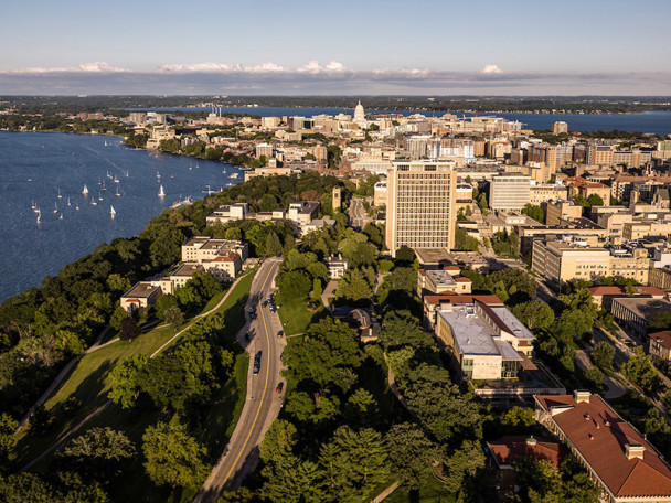 The Madison skyline, state capitol building, and Lake Mendota are seen from a drone that is flying above central campus.