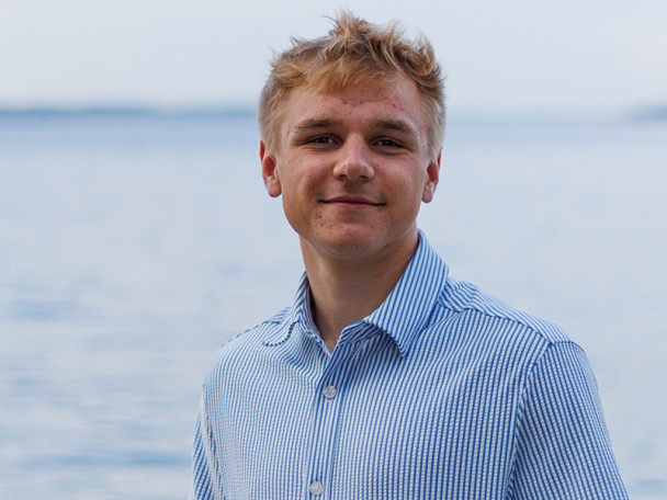 Wyatt Vail, wearing a pinstriped button-up shirt outdoors, with a lake in the background.