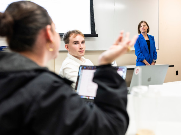 Wichowsky stands at the front of the classroom and listens to a student speaking during the class.