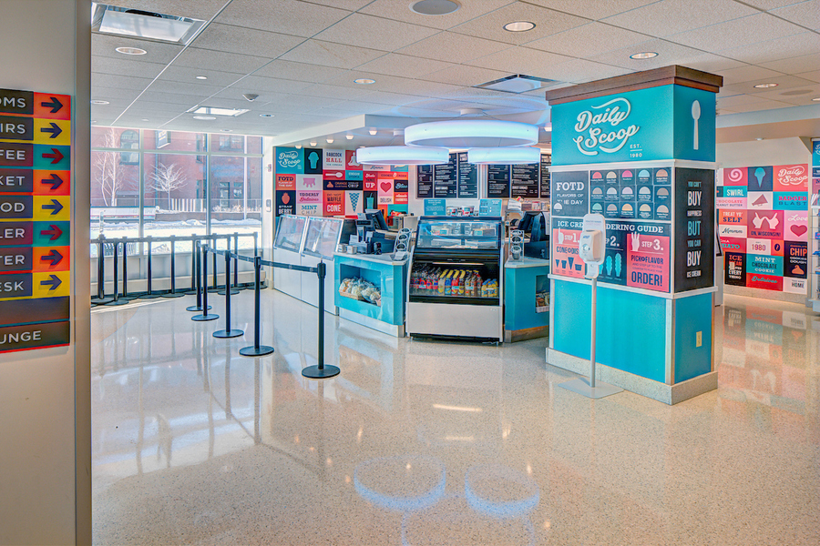 Wide shot of Daily Scoop ice cream coolers, collage wall and menu boards.