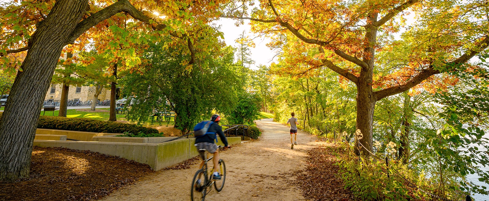 People bike and jog among the colors of the fall leaves on the Howard Temin Lakeshore Path.