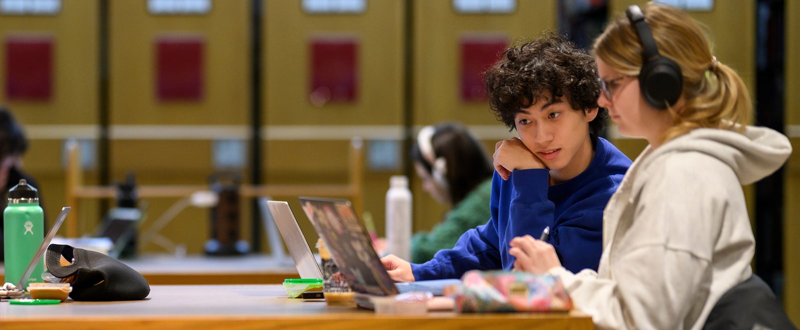 Two people look at a laptop screen in a study area.