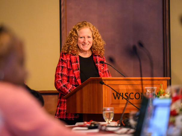 Chancellor Jennifer Mnookin stands behind a podium, smiling.