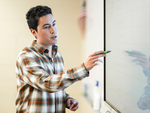 Trueblood writes on a whiteboard at the front of his math classroom.