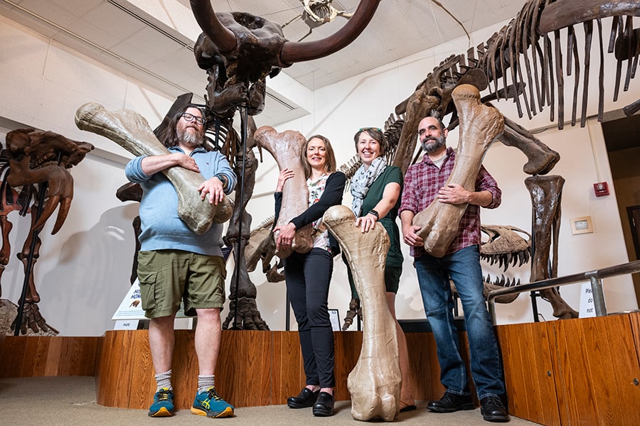 Geology staff pose with replicas of large bones.