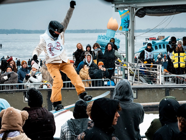 Surrounded by a cheering crowd, a snowboarder slides on a rail at the Memorial Union Terrace.